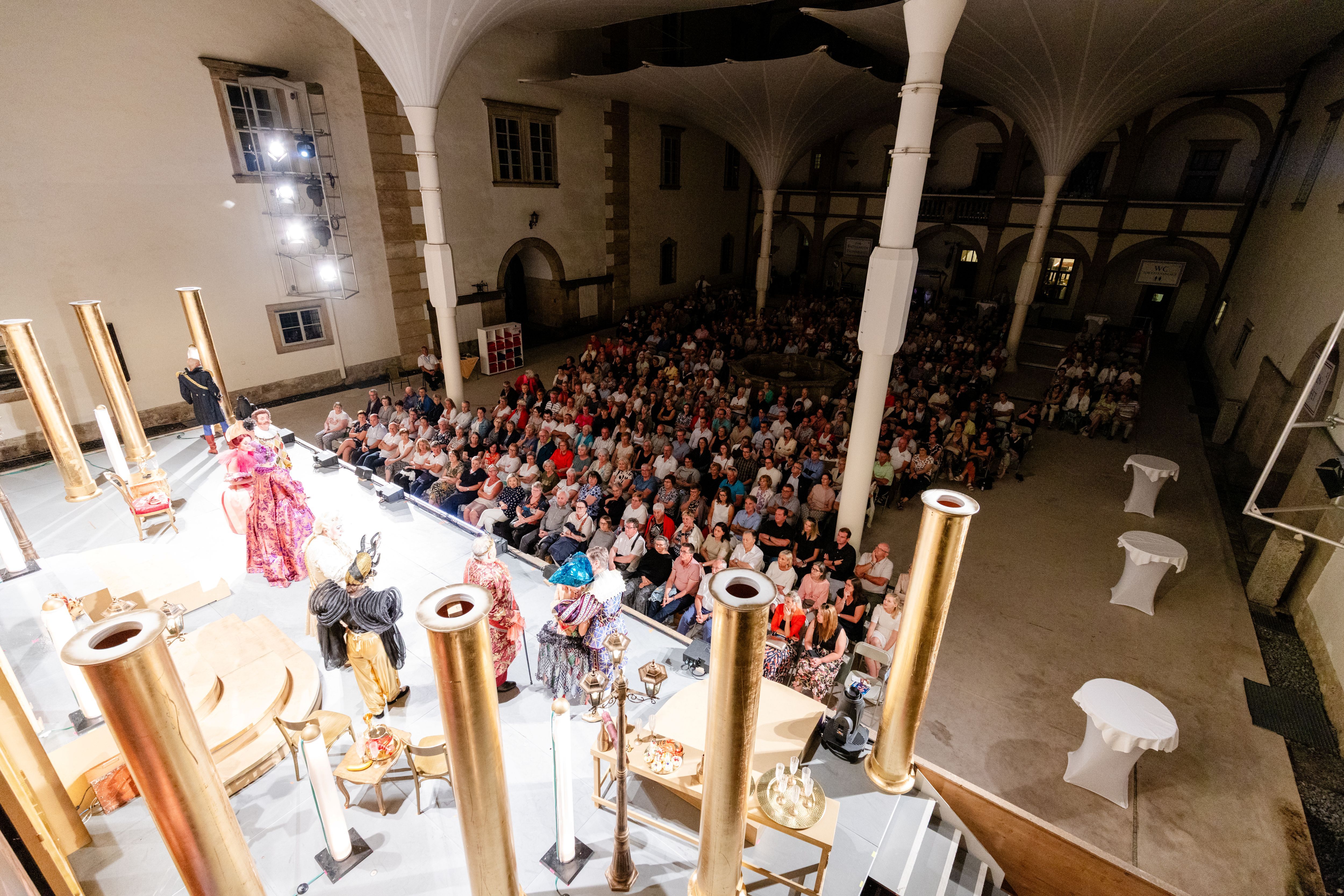 Schloss Weitra Festival. Zu sehen ist das Publikum, die Bühne und die Schirmkonstruktion
