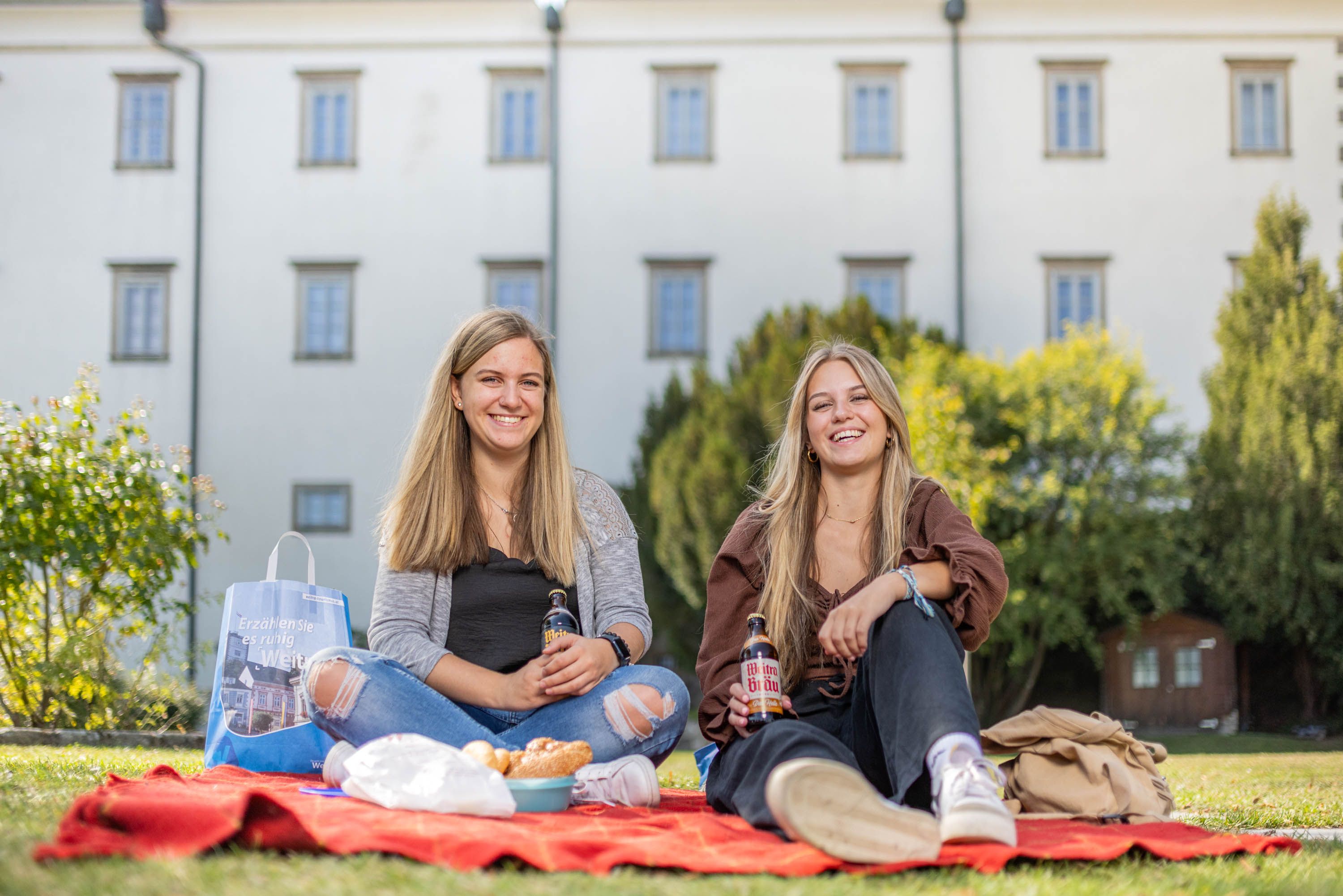 Zwei junge Frauen machen ein Picknick. Im Hintergrund ist Schloss Weitra zu sehen.