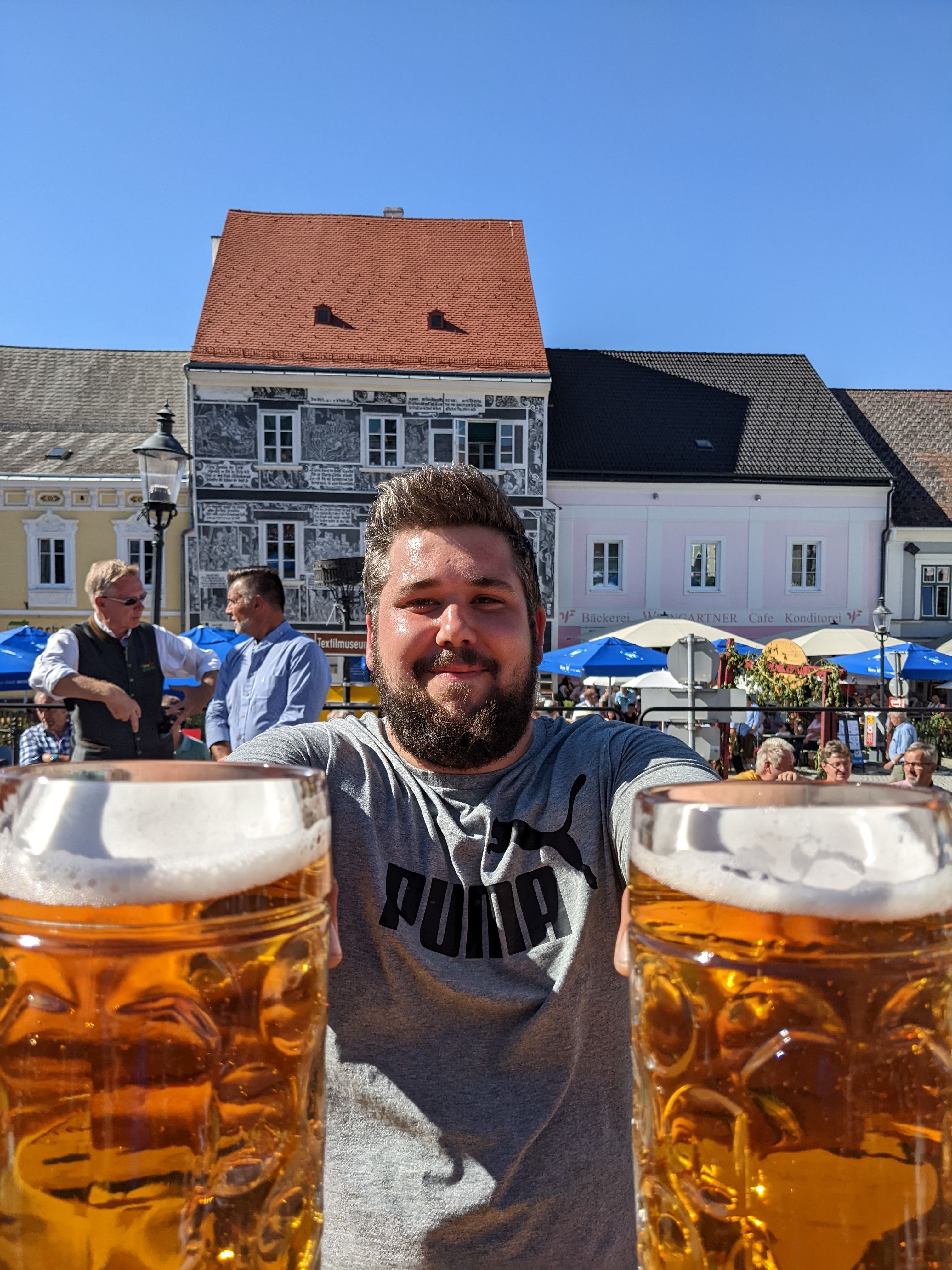 Ein Mann stemmt 2 große Biergläser.