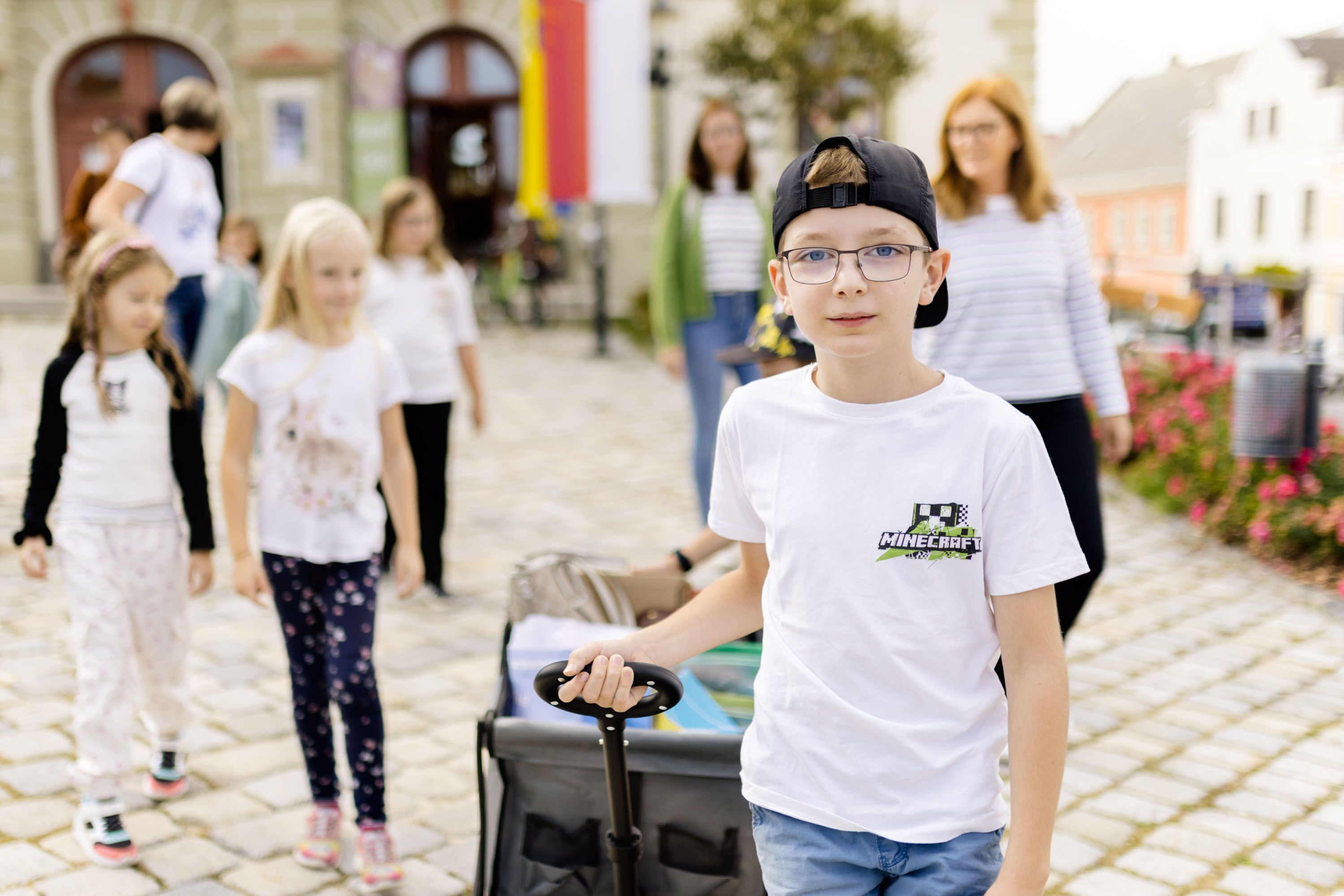 Weitra: Eine Gruppe Kinder bei einer Stadtführung. Der Junge im Vordergrund zieht einen Bollerwagen.