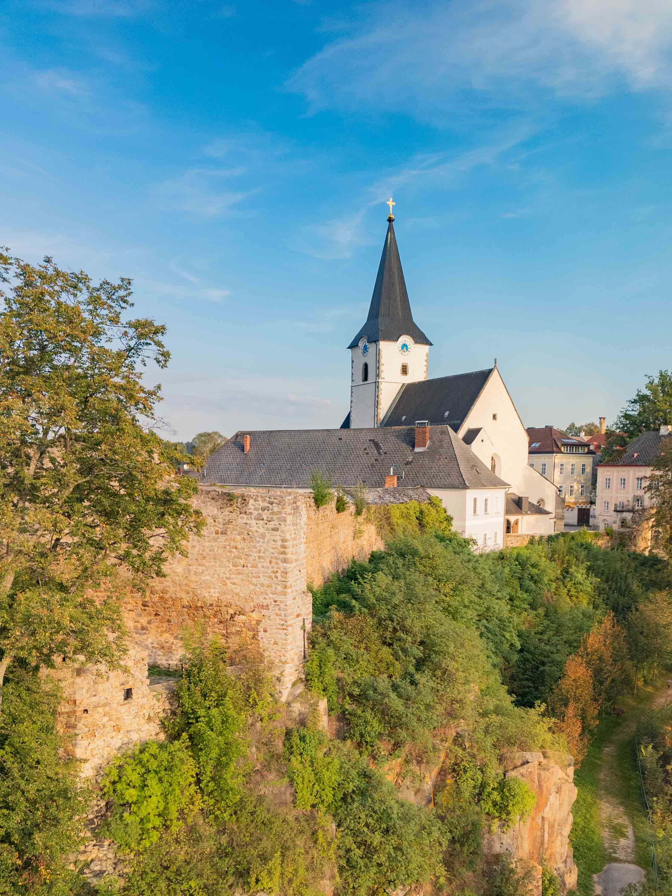Drohnenaufnahme von Weitra, im Vordergrund die mittelalterliche Stadtmauer, im Hintergrund die Stadtpfarrkirche