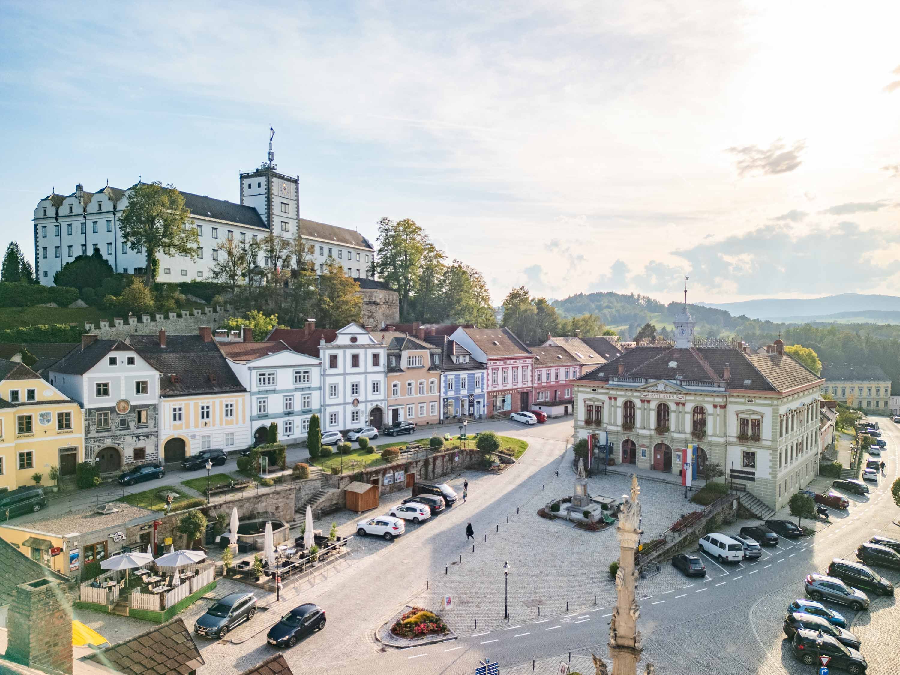 Ein Drohnenfoto von der Altstadt von Weitra. Zu sehen ist zentral das Rathaus sowie der Platz mit historischen Häusern sowie im Hintergrund Schloss Weitra.