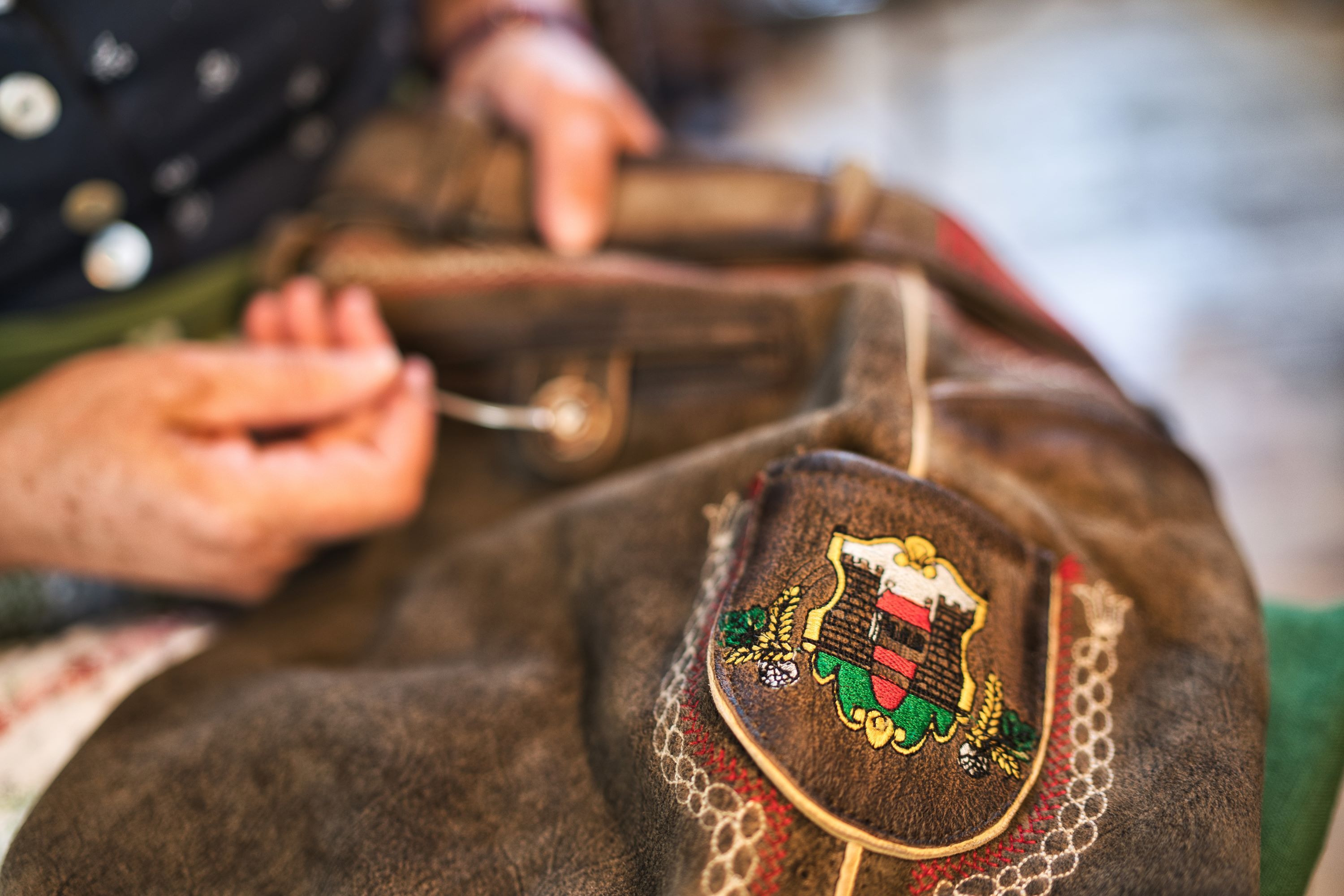 Weitra: Nahaufnahme Nähen einer Lederhose mit Weitra Wappen