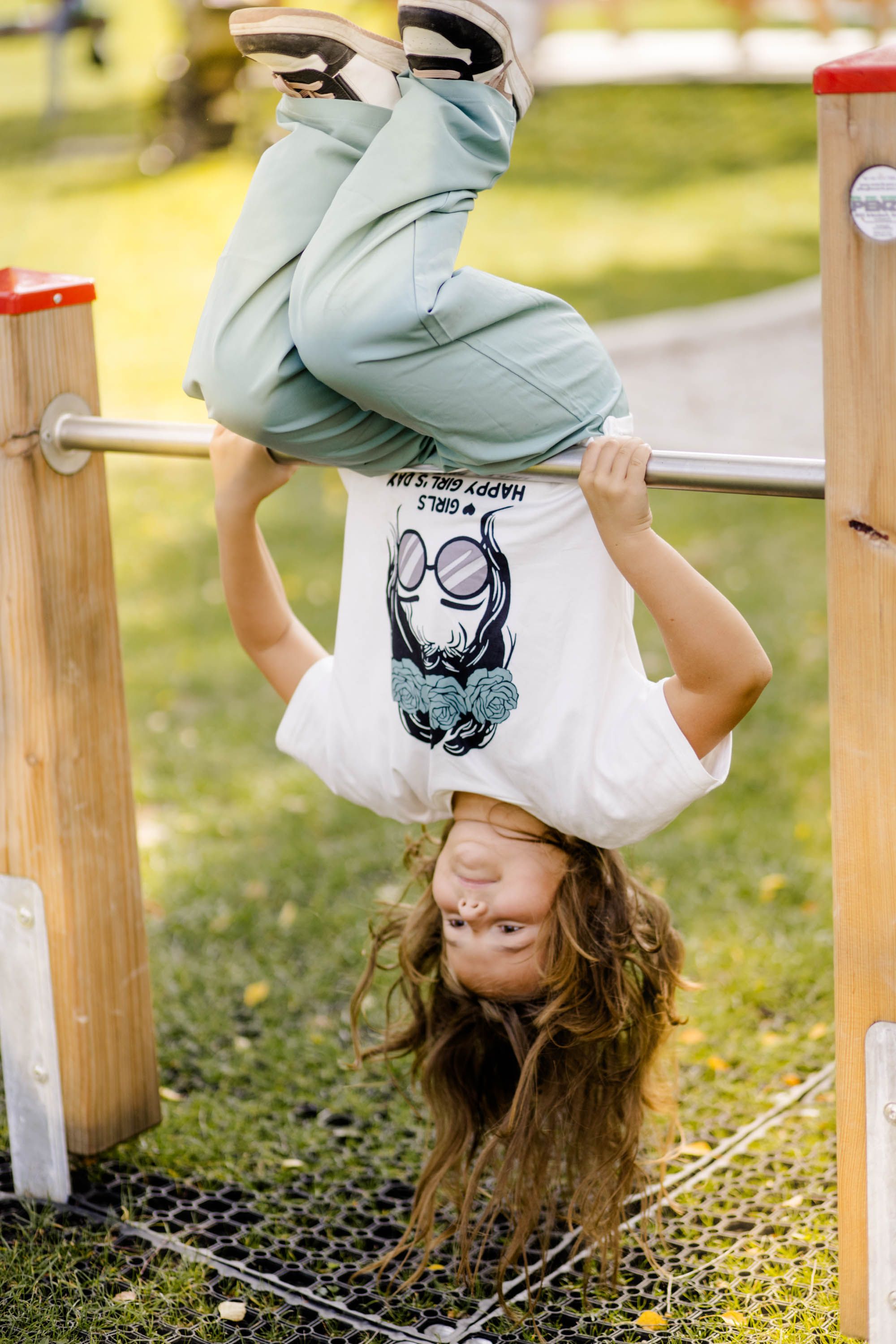 Weitra: Ein Mädchen auf dem Spielplatz. Sie hängt kopfüber von einer Stange.
