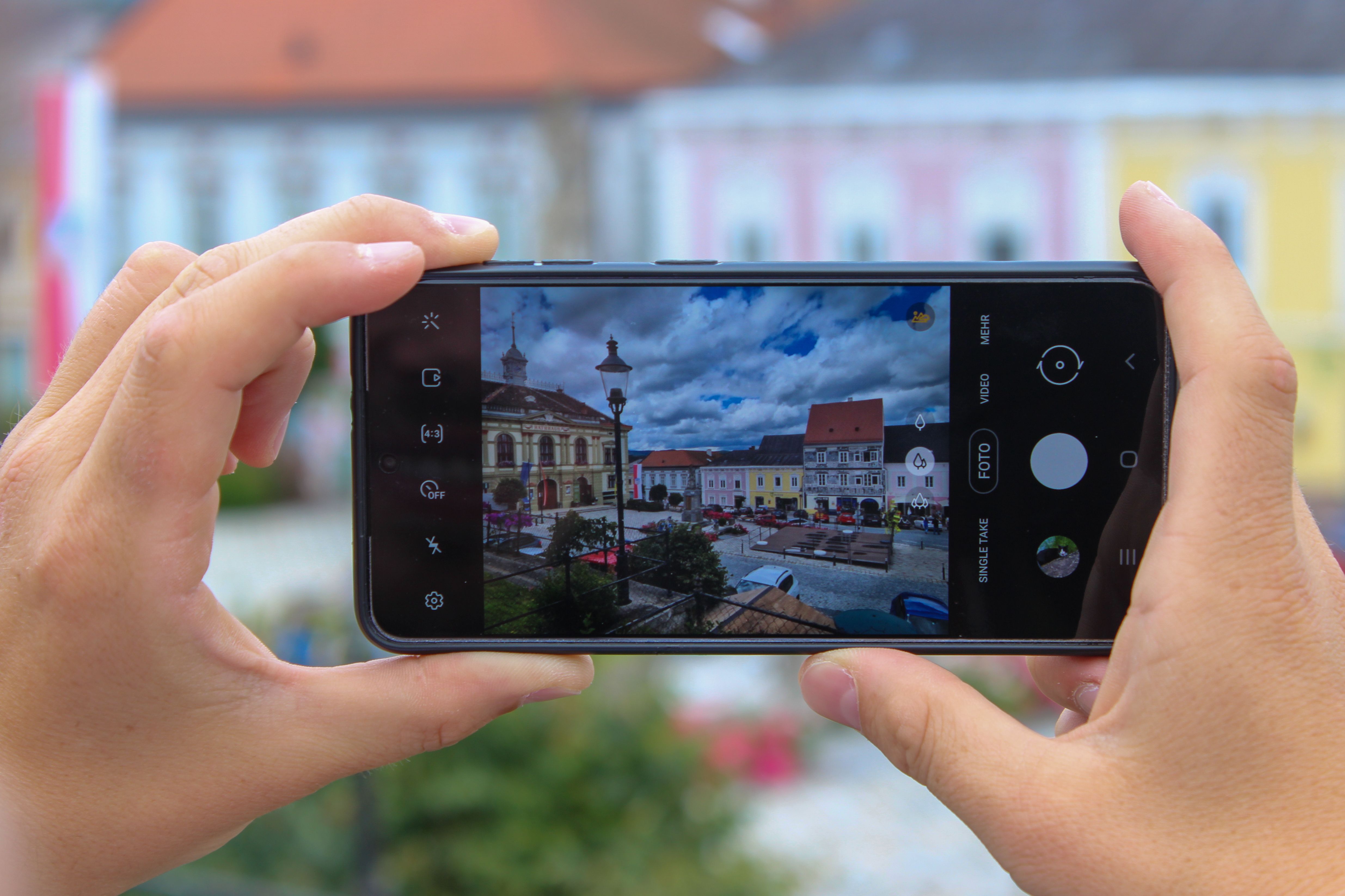 Im Vordergrund ein Smartphone, auf dem Bildschirm sieht man die historischen Bürgerhäuser von Weitra