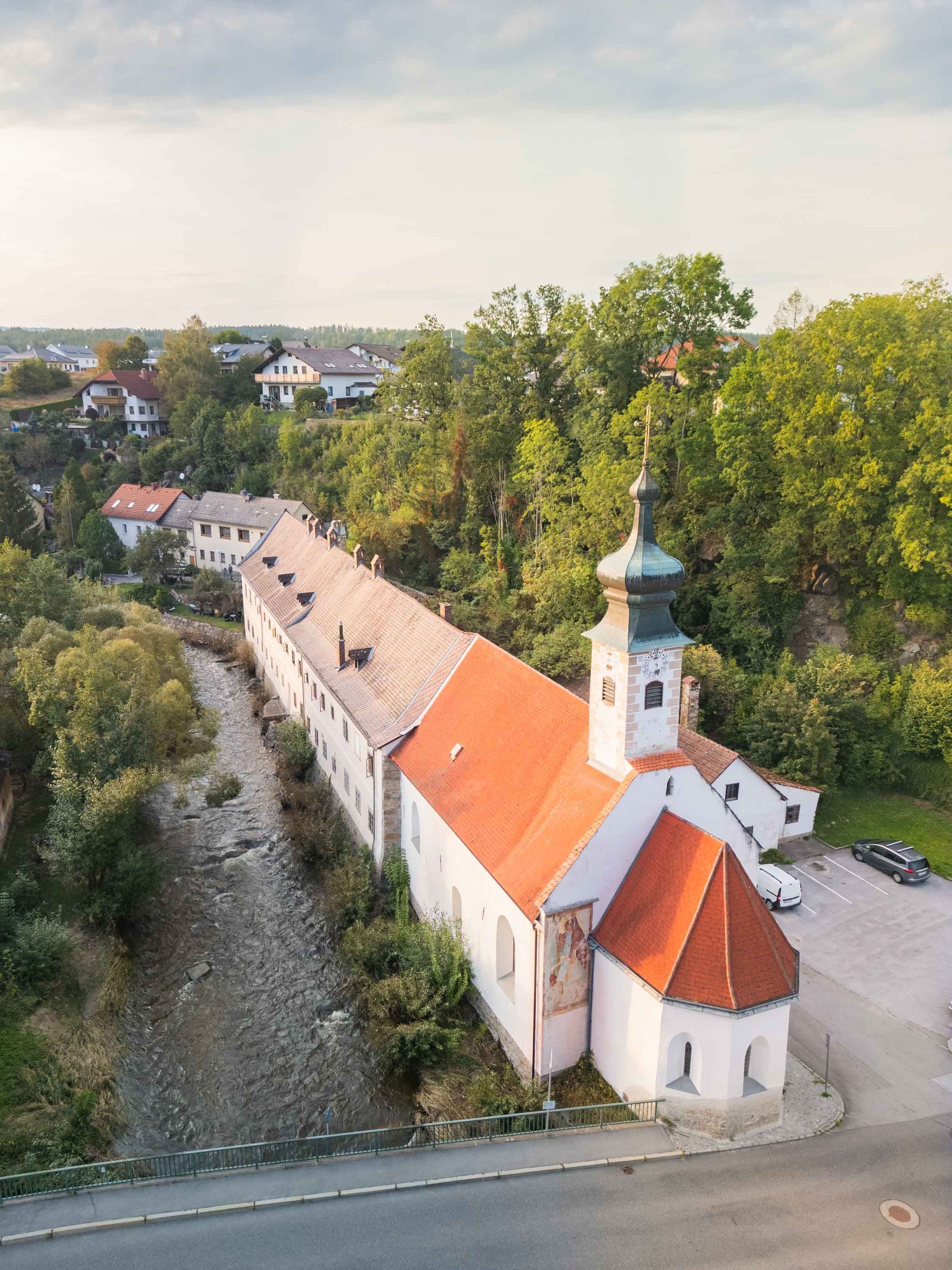 Drohnenaufnahme vom historischen Bürgerspital und der Spitalkirche in Weitra, daneben die Lainsitz