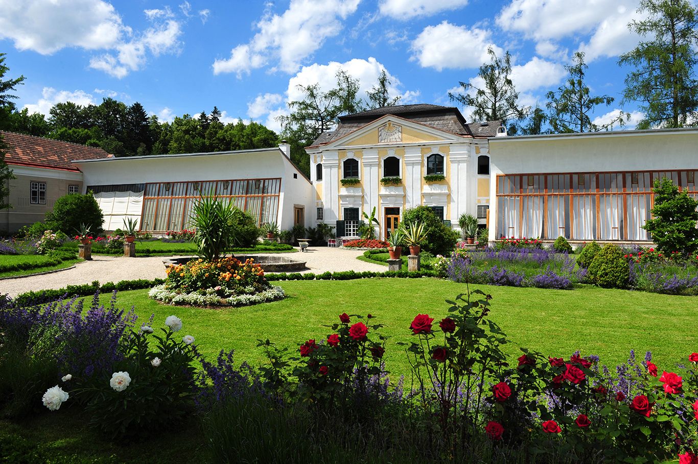 Orangerie des Stifts Zwettl mit gepflegtem Garten und blühenden Blumen.