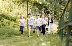 Eine Gruppe Kinder läuft einen grünen Weg entlang auf die Kamera zu.