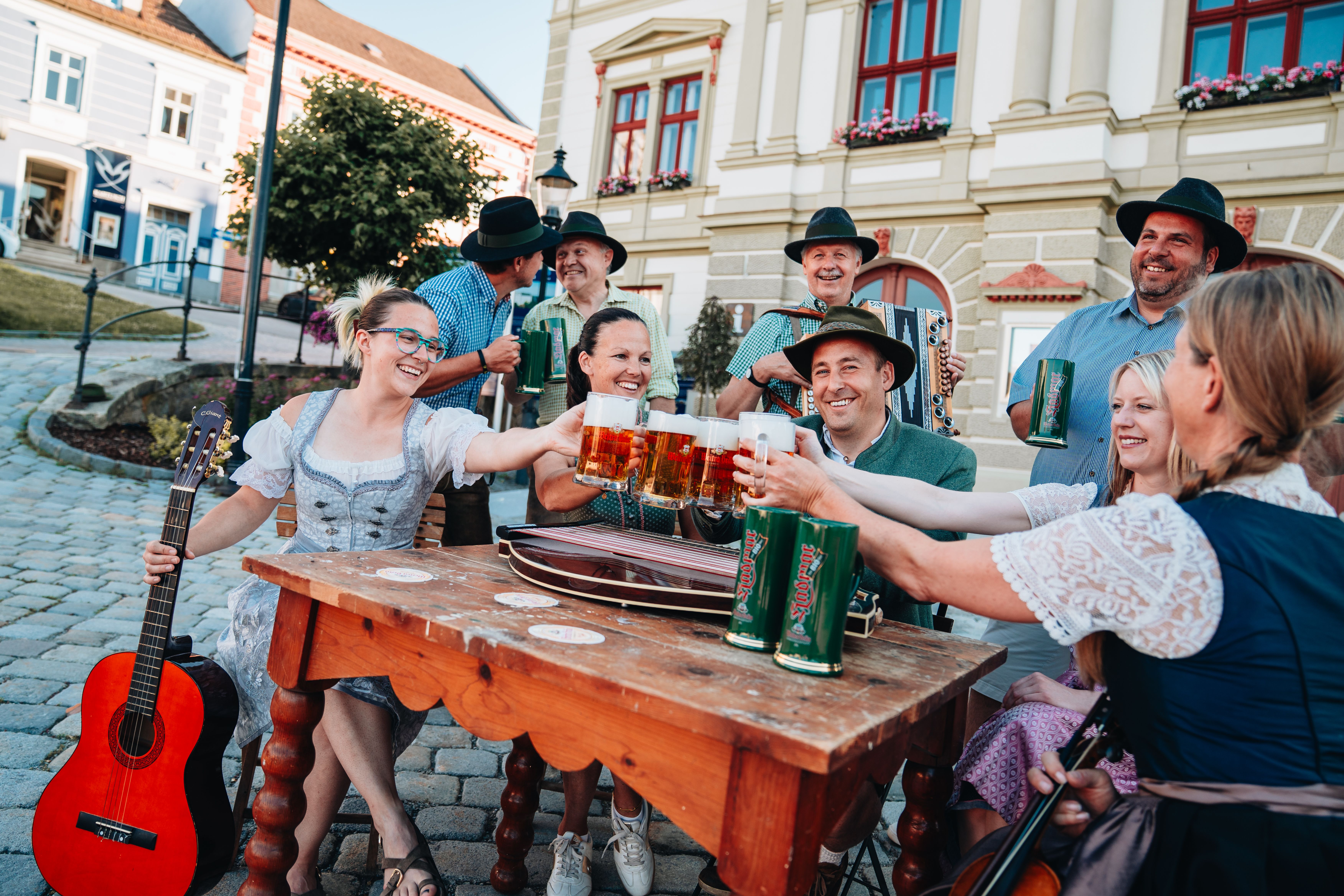 Eine Gruppe Menschen in Tracht stoßen mit einem Bier an.