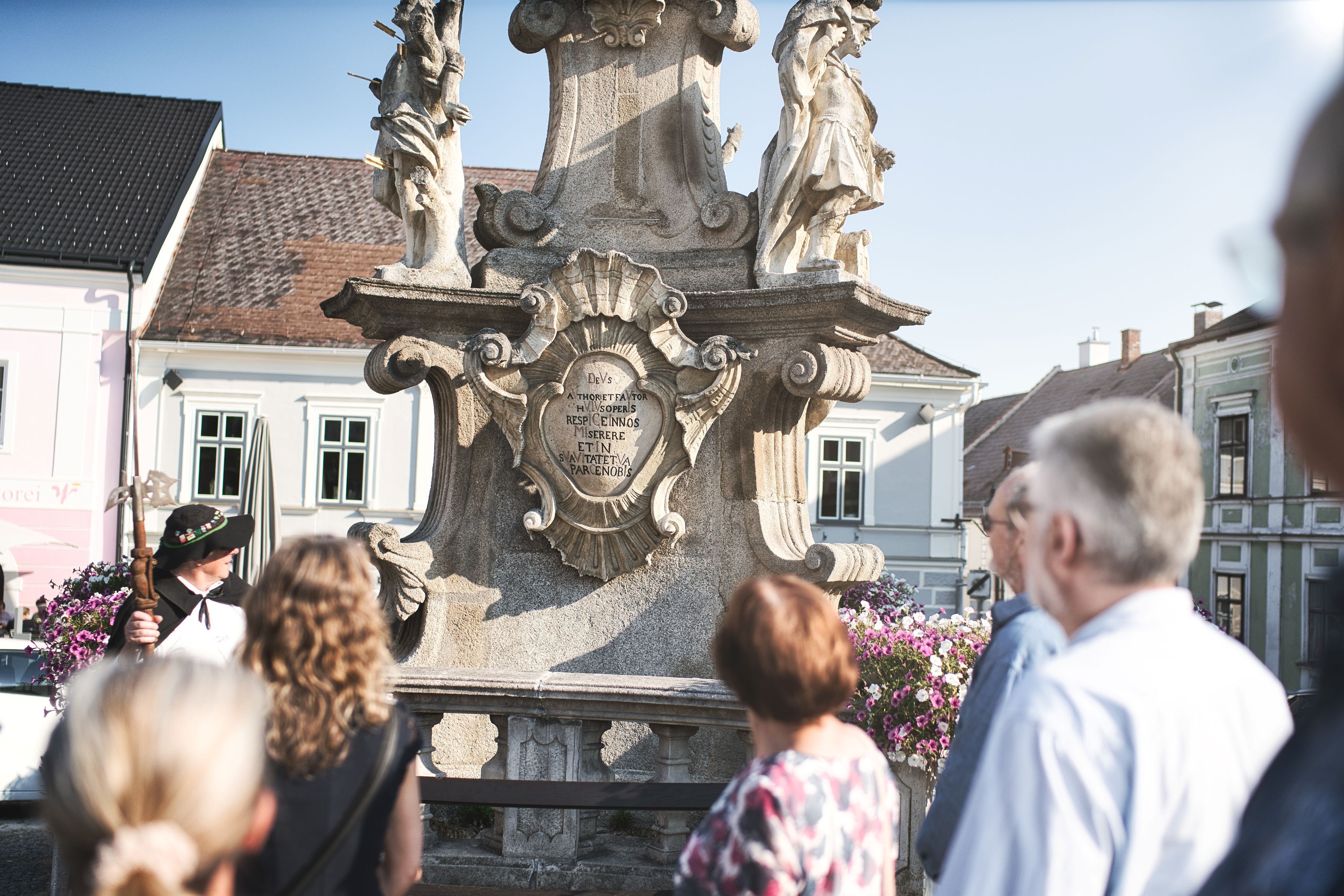 Der Nachtwächter zu Weitra und eine Gruppe Personen vor der Pestsäule in Weitra.